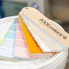 Ventaglio di campioni di colori per la tintometria, con tonalità pastello e vivaci, su secchi bianchi.