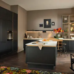 Cucina moderna con mobili neri e dettagli dorati, un'isola centrale con frutta e un tappeto dai colori caldi che aggiunge un tocco accogliente.