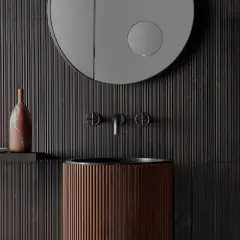 Bagno moderno con lavabo in legno scanalato, rubinetteria in metallo scuro e specchio rotondo. Parete con un suggestivo effetto bambù.