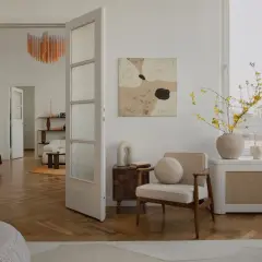Un soggiorno in stile **organic modern** con mobili chiari, parquet a spina di pesce e un quadro astratto.