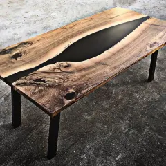 Tavolo in legno con venature naturali e un inserto centrale di resina per tavoli nera, che crea un contrasto moderno e affascinante.