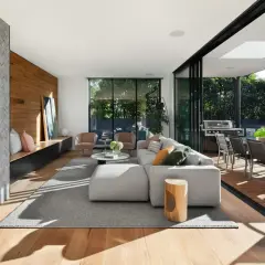 Soggiorno moderno con camino in pietra, parete in legno e diverse tipologie di legno per pavimenti e arredi.
