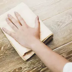 Mano che pulisce un pavimento in legno con un panno, per rimuovere lo sporco e far brillare il legno annerito.