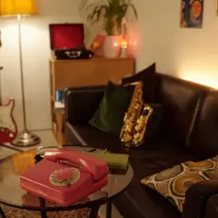 Un salotto in stile dark academia con chitarra rossa, sassofono, telefono vintage e giradischi.