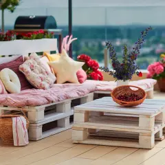 Divano e tavolino da caffè creati con il riciclo pallet, decorati con cuscini colorati, fiori e una cesta di ciliegie.