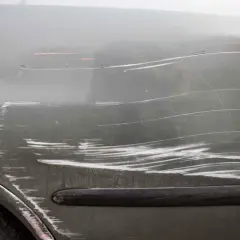 Dettaglio di una portiera d'auto con numerosi graffi superficiali e profondi, che illustrano vari tipi di graffi auto.