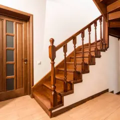 Una pittura di scale in legno scuro, con una porta in legno a sinistra e un'altra porta in legno a destra.