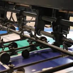Meccanismi di una macchina da stampa con fogli colorati che attendono la vernice UV per una finitura brillante.