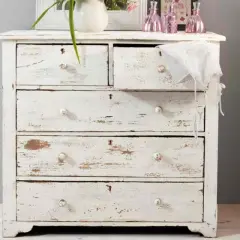 Comò in legno decapato bianco, con cassetti consumati che raccontano storie di un tempo.