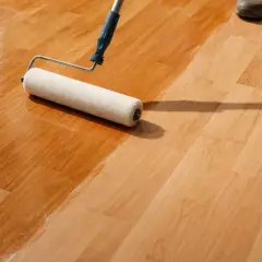 Rullo applica verniciatura poliuretanica su parquet. La finitura lucida protegge il legno.