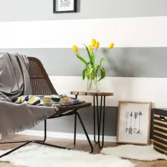 Un angolo accogliente con sedia, cuscino decorativo e tulipani gialli. Ispirazione per come dipingere le pareti di casa con strisce grigie e bianche.
