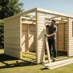 Uomo che costruisce un porta attrezzi da giardino fai da te in legno. Strumenti e assi di legno sul prato.