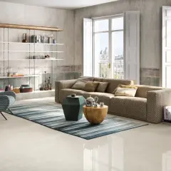 Salotto moderno con divano chevron, poltrona a zig-zag e scaffali bianchi. Pavimento in gres porcellanato color avorio.