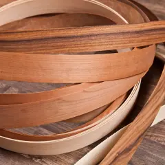 Nastri di impiallacciatura in legno di diverse tonalità, con un effetto plastica che ne esalta la texture naturale.