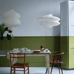 Tavola apparecchiata con sedie in legno, lampade bianche e pareti bicolore: un esempio di eleganti verde oliva abbinamenti.
