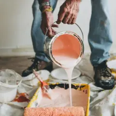 Mani versano pittura murale a spruzzo in una vaschetta per rulli. Preparazione per un nuovo colore.