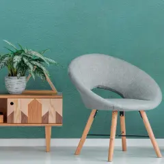 Un angolo relax con sedia grigia, tavolino di legno e un libro aperto, su una parete con pittura satinata color acquamarina.