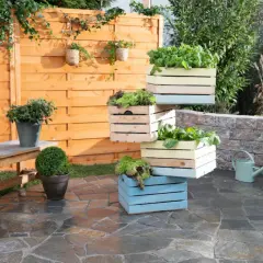 Fioriere in legno fai da te impilate, piene di verdure fresche, creano un angolo verde su un patio in pietra.