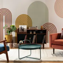 Salotto con poltrone colorate, mobile bar con giradischi e vinili, tavolino verde acqua e decorazioni murali in stile mid century.
