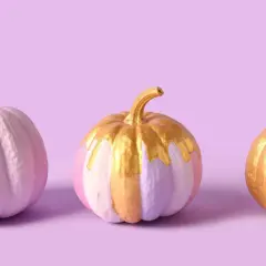 Tre zucche dipinte in tonalità pastello e oro, con un tocco scintillante.