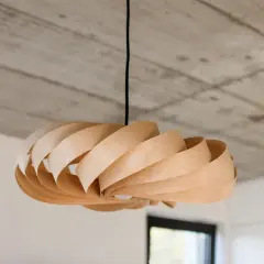 Lampada fai da te in legno, con lamelle curve che creano un effetto a spirale. Un pezzo unico che illumina con stile.