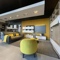 Un soggiorno moderno con divano grigio, cuscini e coperta senape colore, poltrona gialla vivace e parete di fondo color ocra.