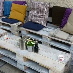 Un accogliente divano fai da te realizzato con pallet, decorato con cuscini colorati e un tavolino, perfetto per un angolo relax.