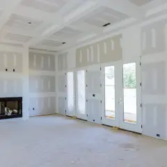 Interni di una casa in costruzione, con pareti e soffitto in cartongesso pronti per essere stuccati. Si intravede un camino.