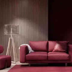 Divano e poltrona in velluto color bordeaux, con tappeto e parete coordinati. Lampada da terra con paralume trasparente.