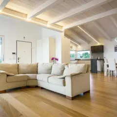 Soggiorno moderno con travi in legno di bianco, divano beige e cucina a vista.