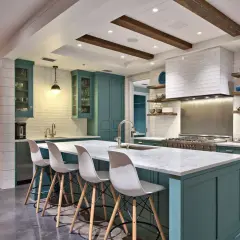 Cucina moderna con isola centrale, sgabelli bianchi e mobili color petrolio. La scelta tra meglio vernice opaca o lucida per i pensili è un dettaglio che fa la differenza.