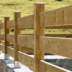 Staccionata in legno fai da te, con montanti robusti e assi orizzontali, che delimita un prato verde.