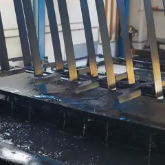 Parti metalliche immerse in un bagno per il trattamento fosfatante, pronte per la verniciatura.