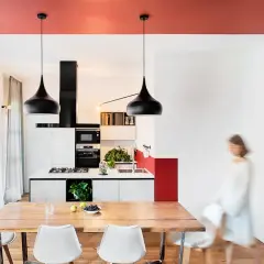 Un soggiorno moderno con soffitti colorati, un tavolo in legno, sedie bianche e una cucina a vista.