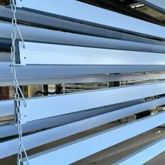 Profili in ferro azzurro appesi a catene, pronti per essere verniciati o dopo aver subito un processo di smerigliare ferro.