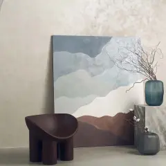 Parete con finitura materica, un quadro astratto e una poltrona dal design organico. La **decorative paint** crea un'atmosfera rilassante.