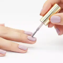 Applicazione smalto lilla su unghie. Il tempo asciugatura vernice smalto è fondamentale per un risultato perfetto.