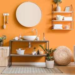 Bagno moderno con pareti arancioni vivaci, lavabo, vasca e accessori che creano un'atmosfera accogliente. I colori per bagno sono scelti con cura per un ambiente rilassante.