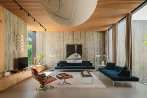 Interni in stile brutalist con pareti in cemento grezzo, soffitto in legno e mobili moderni.