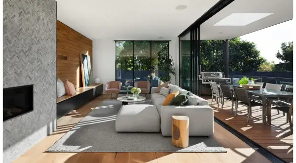 Soggiorno moderno con camino in pietra, parete in legno e diverse tipologie di legno per pavimenti e arredi.