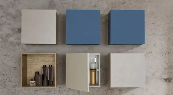 Composizione di pensili a muro: due blu, uno color corteccia con bottiglie, uno aperto con vasi, e due chiusi in tonalità neutre.