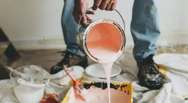 Mani versano pittura murale a spruzzo in una vaschetta per rulli. Preparazione per un nuovo colore.