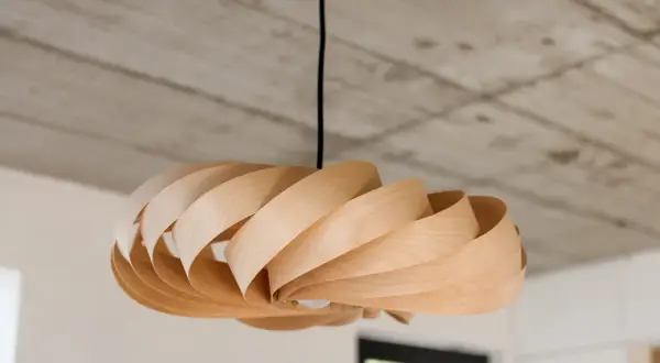 Lampada fai da te in legno, con lamelle curve che creano un effetto a spirale. Un pezzo unico che illumina con stile.