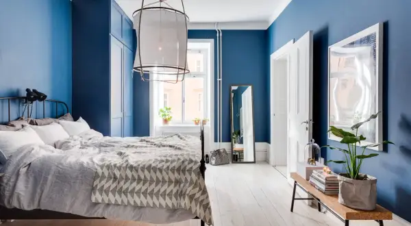 Camera da letto con accogliente parete azzurra, letto comodo, armadio blu e pavimento in legno chiaro.