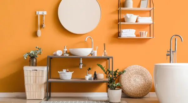 Bagno moderno con pareti arancioni vivaci, lavabo, vasca e accessori che creano un'atmosfera accogliente. I colori per bagno sono scelti con cura per un ambiente rilassante.