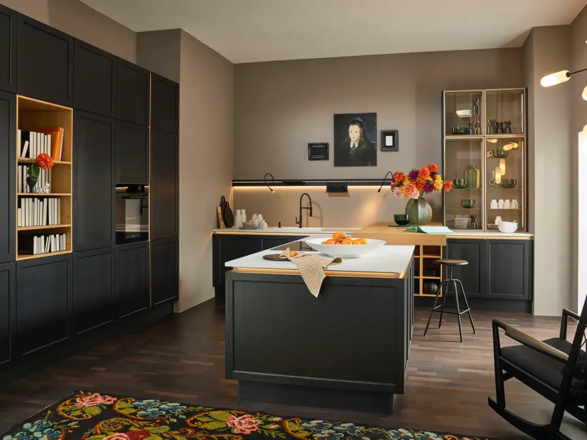 Cucina moderna con mobili neri e dettagli dorati, un'isola centrale con frutta e un tappeto dai colori caldi che aggiunge un tocco accogliente.