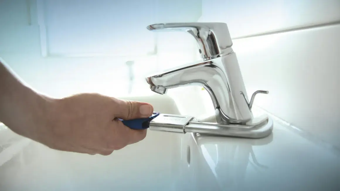 Mano con chiave per cambiare rubinetto lavandino bagno.