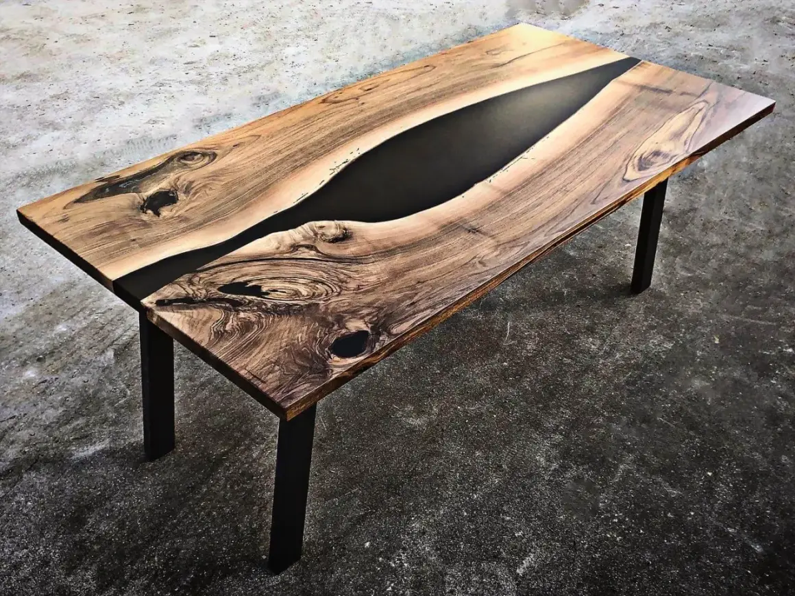 Tavolo in legno con venature naturali e un inserto centrale di resina per tavoli nera, che crea un contrasto moderno e affascinante.