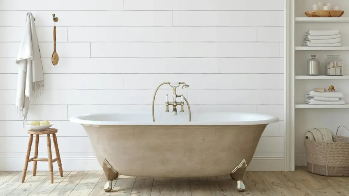 Bagno moderno con vasca da bagno color sabbia, rubinetteria dorata e asciugamani bianchi. Un progetto di verniciare vasca da bagno per un look rinnovato.