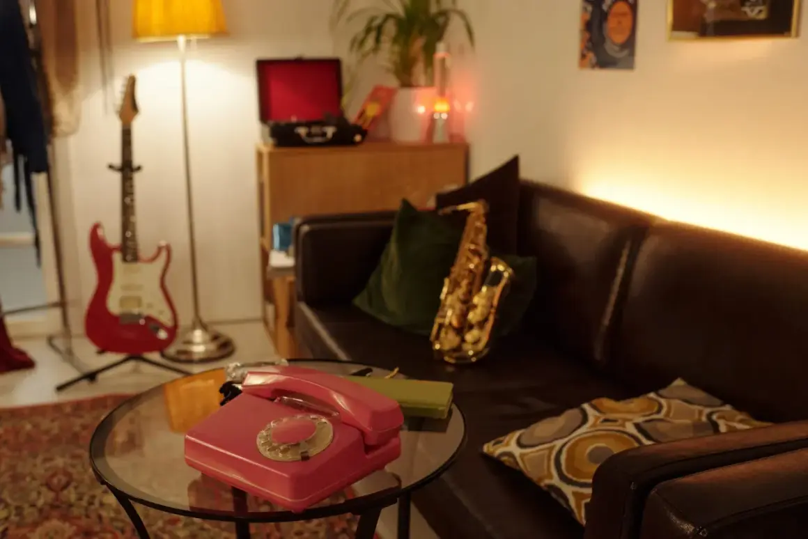 Un salotto in stile dark academia con chitarra rossa, sassofono, telefono vintage e giradischi.